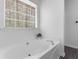 Soaking tub beneath a large window, creating a serene and relaxing bathroom space at 135 Kimbell Farm Dr, Locust Grove, GA 30248