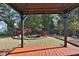 View of a backyard with a pond, small bridge, mature trees and a covered patio at 1112 Autumn Glen Way, Dacula, GA 30019