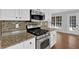 Close up of stainless gas range in kitchen with granite countertops and tile backsplash at 1112 Autumn Glen Way, Dacula, GA 30019