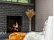 Close up of a painted brick fireplace with a wood burning fire and stylish decor at 3365 Ardley Sw Rd, Atlanta, GA 30311