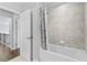 Clean bathroom features neutral tile surround and a shower with tub with door to hall at 4466 Woodland Bank Blvd, Buford, GA 30518