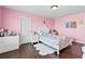This pink bedroom is spacious with white furniture, hardwood floors and large window at 4466 Woodland Bank Blvd, Buford, GA 30518