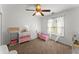 Bright bedroom with pink accents, a ceiling fan, and a window with sheer curtains and blinds at 5381 Fawn Meadow Ln, Powder Springs, GA 30127