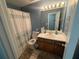 A blue toned bathroom with a shower and tub combination, a large mirror, and a vanity at 221 Huntington Dr, Mcdonough, GA 30253