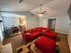 Open-concept living room with red sectional seating, fireplace, ceiling fan, and connecting dining area at 221 Huntington Dr, Mcdonough, GA 30253