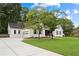 Beautiful white brick home showcasing a lush front lawn, mature trees, and an attached garage at 3860 Rajean Dr, Lawrenceville, GA 30044