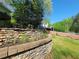 Stone retaining wall with a flower bed near the backyard wooded area and fencing at 60 Bartlett Way, Dallas, GA 30157