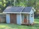 View of a backyard shed featuring stone accents, wood door, roof shingles, and painted blue siding at 60 Bartlett Way, Dallas, GA 30157