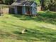 Spacious backyard with green grass and a shed, along with chickens pecking the ground at 60 Bartlett Way, Dallas, GA 30157