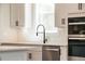 Close up of kitchen featuring stainless steel dishwasher and oven below a window at 4202 Adler Cir, Buford, GA 30519