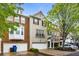 Charming townhome featuring a brick facade, white trim, attached garage, and inviting curb appeal with mature trees at 11302 Musette Cir, Alpharetta, GA 30009