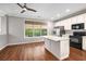 Bright kitchen features white cabinets, stainless steel appliances, granite countertops and a center island on dark hardwood floors at 11302 Musette Cir, Alpharetta, GA 30009