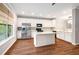 Bright kitchen features white cabinets, stainless steel appliances, granite countertops and a center island on dark hardwood floors at 11302 Musette Cir, Alpharetta, GA 30009