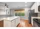 Bright kitchen features white cabinets, stainless steel appliances, granite countertops and a center island on dark hardwood floors at 11302 Musette Cir, Alpharetta, GA 30009