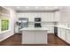 Bright kitchen features white cabinets, stainless steel appliances, granite countertops and a center island on dark hardwood floors at 11302 Musette Cir, Alpharetta, GA 30009
