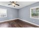 An empty bedroom with hardwood floors, two windows, ceiling fan, and light gray paint at 1441 Cahaba Sw Dr, Atlanta, GA 30311
