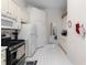 Well-lit kitchen featuring white cabinets and appliances, with a view into the adjacent dining area at 5494 White Cedar Ter, Sugar Hill, GA 30518