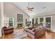 Cozy living room with a fireplace, hardwood floors, a ceiling fan, and large windows at 3665 Evonvale Gln, Cumming, GA 30041