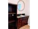 Bathroom vanity with a dark wood finish, granite countertop, and a round mirror at 3735 Fir Dr, Buford, GA 30518