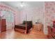 Charming bedroom features a four-poster bed, hardwood floors, and bright, patterned wallpaper at 2016 Westbourne Way, Johns Creek, GA 30022