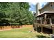 View of the spacious backyard with a wooden deck, fence, mature trees and green grass at 3070 Jardin Nw Ln, Kennesaw, GA 30152