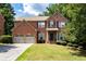 Traditional brick home with a two car garage, manicured lawn, and mature trees in a well-kept neighborhood at 3070 Jardin Nw Ln, Kennesaw, GA 30152