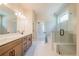 Light filled bathroom features a double sink vanity and glass enclosed shower and tub at 3962 Adler Cir, Buford, GA 30519