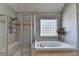 Elegant bathroom with a glass shower, a soaking tub, and a tile window at 2123 Floral Ridge Dr, Dacula, GA 30019