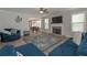 Spacious living room with plush blue furniture, a ceiling fan, a fireplace, and lots of natural light at 7751 Capps Ridge Ln, Douglasville, GA 30135