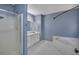 Relaxing bathroom features a glass shower, soaking tub, white cabinets and fixtures, and blue walls at 501 Woodland Trce, Woodstock, GA 30189