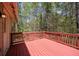 Spacious red wooden deck with a view of the surrounding trees and exterior of the house at 501 Woodland Trce, Woodstock, GA 30189