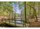 Wooden bridge crossing creek with lake and dock in distance creates a peaceful wooded scenery at 934 Pine Cir, Woodstock, GA 30189