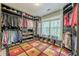 A large walk-in closet with custom shelves, shoe storage, colorful patterned rug, and view to the outside at 1745 Mary Lou Ln, Atlanta, GA 30316