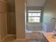 Clean bathroom with a tub, window, and partial view of glass enclosed shower at 5719 Star Flower Dr, Ellenwood, GA 30294