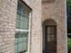 Brick exterior with an arched doorway featuring a door with window panes and secure lock at 1835 Morning Star Ln, Tucker, GA 30084