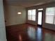 Bright living room with hardwood floors, a black door, and large windows with blinds at 1835 Morning Star Ln, Tucker, GA 30084
