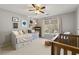 Cozy bedroom featuring a daybed, crib, ceiling fan, and a bright window with natural light at 1888 Fox Chapel Se Dr, Smyrna, GA 30080