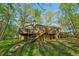 Home featuring large back deck, greenery, and staircase to the yard at 230 Oakmere Dr, Alpharetta, GA 30009