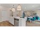 Open kitchen with stainless steel appliances, an island with a sink, and an adjacent dining and living area at 2336 Cadenza Cir, Dacula, GA 30019