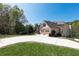 A home with an attached two-car garage and a spacious driveway, surrounded by mature trees and a green lawn at 5095 Hamby Hollow Ln, Cumming, GA 30028