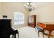 Sunlit room with two pianos, large window with shutters, and elegant chandelier at 5095 Hamby Hollow Ln, Cumming, GA 30028