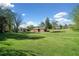 Expansive front yard with lush green grass and mature trees surrounding a brick home under a beautiful partly cloudy sky at 630 Cambridge Dr, Marietta, GA 30066