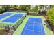 Community tennis courts with multiple blue hard surface courts with fencing and lighting at 335 Wyehwood Ct, Alpharetta, GA 30022