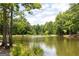 Calm lake view surrounded by green trees and lush greenery reflecting the beautiful sky at 505 Altamaha Court, Locust Grove, GA 30248