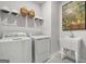 Bright laundry room includes a utility sink, white washer and dryer, and wall shelving for extra storage at 505 Altamaha Court, Locust Grove, GA 30248