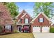Charming two-story brick home featuring a manicured lawn, mature landscaping, and a two-car garage at 1442 Valley Glen Way, Dunwoody, GA 30338