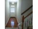Hallway with hardwood floors leads to a staircase with wooden banister and a door at 2162 Oakland Grove Pl, Lawrenceville, GA 30044