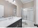 Bathroom featuring a double vanity with marble countertop, dark cabinetry, and a tiled shower-over-tub with sliding doors at 2320 Copper Trail Ln, Buford, GA 30519