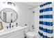 Bright bathroom featuring a round mirror, shower with blue striped shower curtain, and a white quartz countertop at 705 Stewart Nw Cir, Marietta, GA 30064