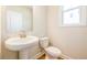 Powder room featuring a pedestal sink, white toilet, and a window at 7505 Woolf Way, Cumming, GA 30028